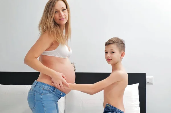 An interesting boy with a pregnant mother at home. embrace.