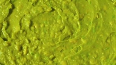 Fresh guacamole sauce swirls close-up background. Zuking healthy food. Making Mexican vegetable guacamole avocado sauce. Guacamole recipe.