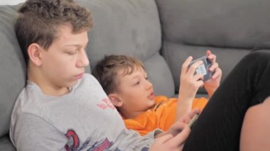 Children with smartphones at home. two boys spend time on social network using mobile phones. White kids use cell phones to play games. Lifestyle concept.