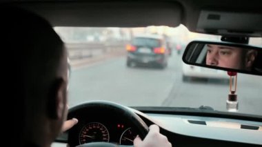 Yolculuk, araba yolculuğu konsepti. Araba sürücüsü, dikiz aynasından. Bir adam elleri direksiyonda araba kullanır.