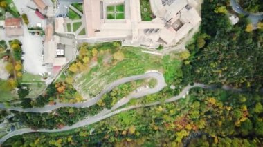 Güneşli sonbahar gününde köyün üzerinde uçan drone 'lar sinematik, canlı, renkli ormanlarla çevrilidir. Manzara sarı, kırmızı, turuncu sonbahar yaprakları. Kırsal bölgeden geçen siyah arazi aracı.