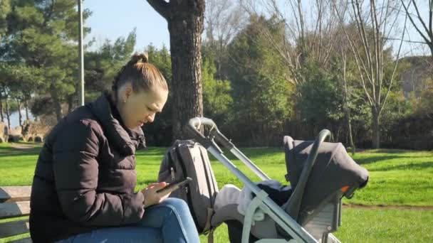 Young Mother Sitting Bench Talking Phone While Holding Stroller Her — Video Stock