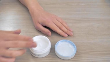 Woman smears her hands with cream. Elderly hands.