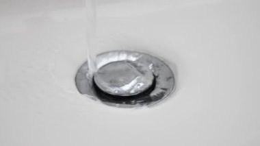 Su lavabo deliğinden aşağı akıyor. Seramik lavaboda yavaş çekim su gideri. Su akıntısı kanalizasyona akıyor, kapatın. Kamu hizmetleri. kanalizasyon