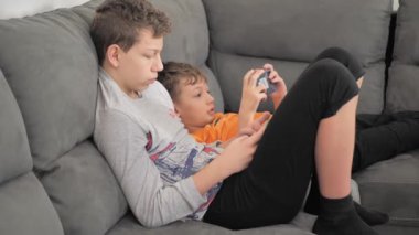 Children with smartphones at home. two boys spend time on social network using mobile phones. White kids use cell phones to play games. Lifestyle concept.