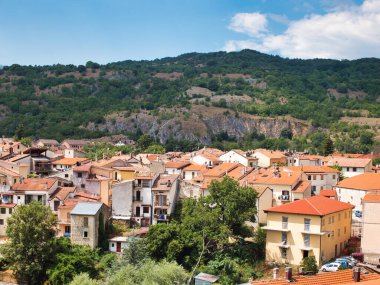 A small town in the mountains of Italy. White old houses with orange tiled roofs stand on the slope