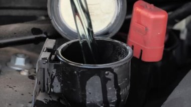 Plastik teneke kutudan araba yıkama sıvısı haznesine sıvı dökme, yakın çekim.