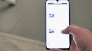 Bir adam şantiyeden araba almayı seçiyor. Akıllı telefon uygulaması almak için kullanılmış araca bakıyorum. Yakın çekim. Ekran bulanık. 4K UHD