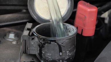 Plastik teneke kutudan araba yıkama sıvısı haznesine sıvı dökme, yakın çekim.