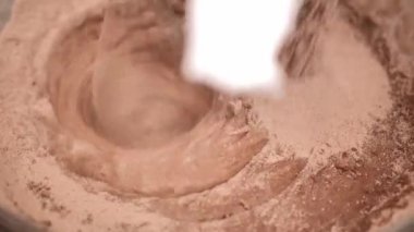 Process of making dough for pancakes with flour in paper bag on light table, eggs, flour beat with mixer. Pancake dough with ingredients beat mixer. Woman beats dough at kitchen table in kitchen