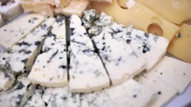 Cut cheese into slices in a buffet bowl, close-up.