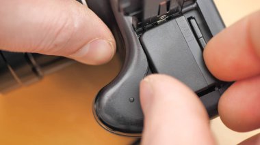 Bir fotoğrafçı çekim sırasında dijital SLR kamerasının pilini değiştirir. Kamera bataryasına odaklan..