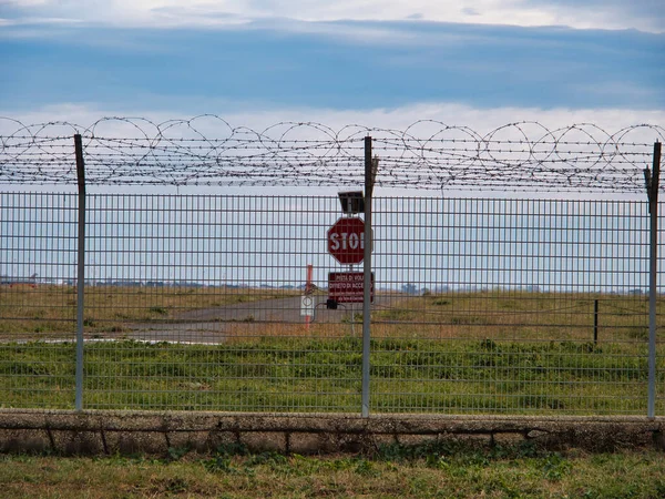 stock image Airport security perimeter fencing system with razor wire with SRA security restricted area stop sign and airplanes behind.