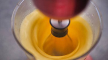 Şeffaf bir bardakta çırpıcı ile yumurta çırp..