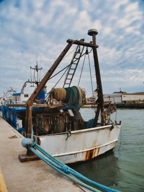 Endüstriyel liman manzarası: rıhtımda demirlemiş eski paslı bir balıkçı teknesi