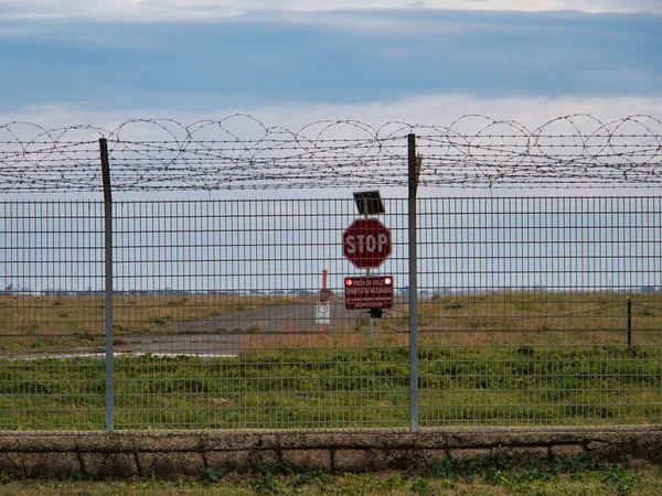 Airport security perimeter fencing system with razor wire with SRA security restricted area stop sign and airplanes behind.