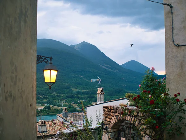 a view from the window to a mountain town, a panorama of mountains, a lantern and tenement houses. A sunny day in an old mountain village built on top of a mountain
