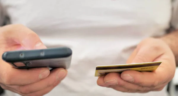 stock image Young man using his smartphone shopping online with a debit or credit card. Using online banking.