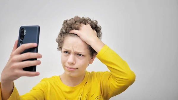 十代の若者は電話を見ている間ににきびを絞る 十代のにきびの問題 — ストック写真