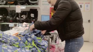 Roma, İtalya, 22 Ocak 2023. Bir kadın İtalyan süpermarketinde kıyafet seçer..