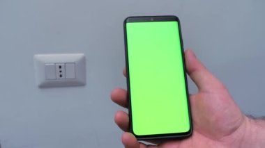 İnternet reklamcılığı. Beyaz arka planda yeşil ekranlı akıllı telefonu tutan bir erkeğin yakın çekimi. Yerleşim ve kopyalama alanı. Programlar ve sosyal ağlar kavramı