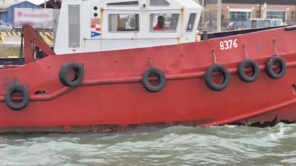 一艘红色的大型干货船在几艘小渔船旁边航行 船尾是水 — 图库视频影像