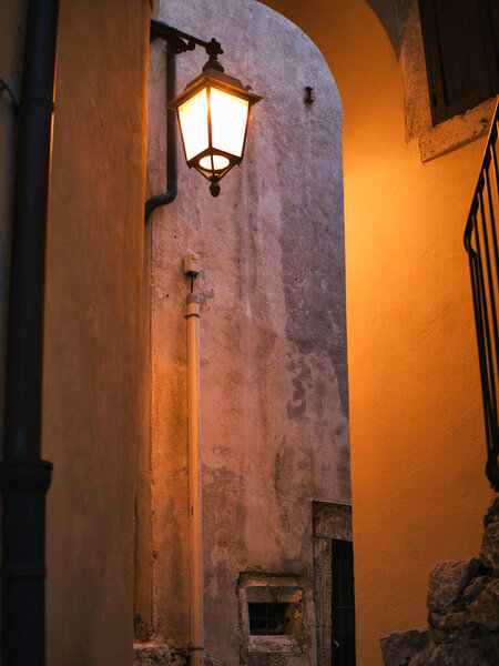 A street lamp illuminates a narrow street in Italy.
