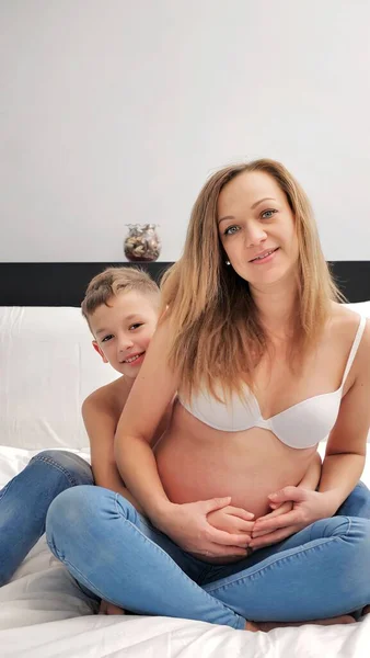 妊娠中のお母さんは寝室で子供と話して遊んでいます 家でリラックスしながら良い感情を共有する息子と母 — ストック写真