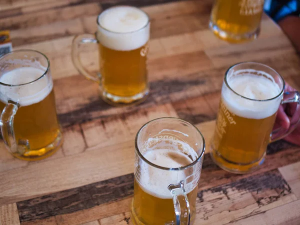 杯子里的淡啤酒在木制桌子上呈圆形陈列着 头顶上的啤酒杯放在木制桌子上 — 图库照片