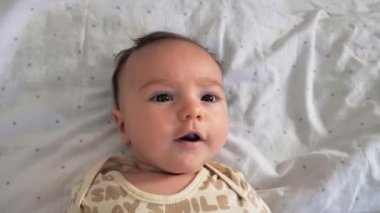 Beyaz bir yatakta yeni doğmuş tatlı bir erkek bebek. Yakın çekim, çocukça duygular..