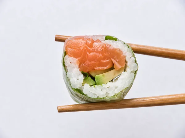 stock image Tasty sushi roll with wooden chopsticks on white background.