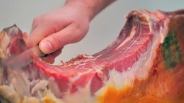 Macro shot of a man sharply slicing a traditional Spanish ham. Close up of hand and blade