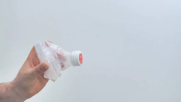 白い背景に押しつぶされたプラスチックボトルを保持男性の手 リサイクルのためのプラスチック廃棄物の収集 プラスチック汚染とあまりにも多くのプラスチックごみの概念 上部のスペースをコピーします — ストック写真