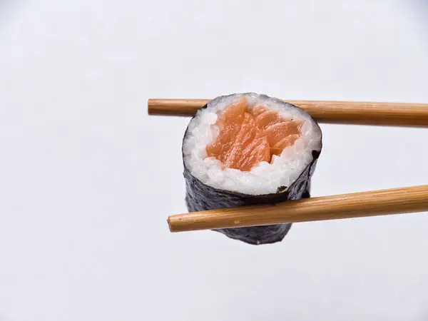 stock image Tasty sushi roll with wooden chopsticks on white background.