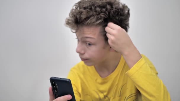 携帯電話を見ている間ににきびを絞る十代の男の子のクローズアップ — ストック動画