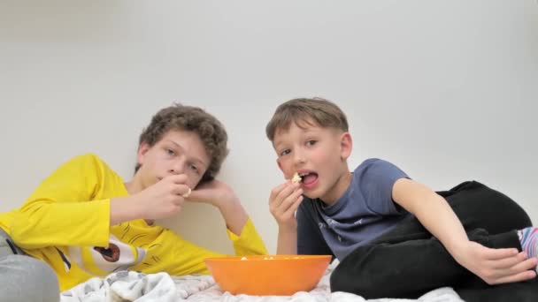 两个懒散的十几岁男孩在电视上看电影 吃爆米花 家庭娱乐 — 图库视频影像