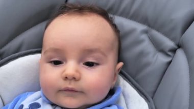 Bebek fotoğraf makinesine yakın çekim yukarı bakışı. Şirin bir bebek kameraya bakıyor. Bebek etrafına bakıyor ve sonra gülümsüyor ve gülüyor. Çocuklar için ebeveyn sevgi bakmakta kavramı.