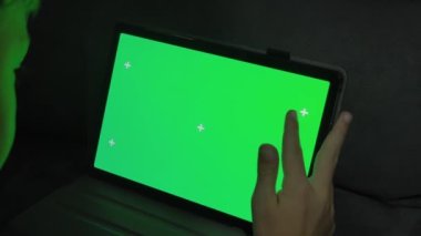 Yeşil ekranlı bir tablet bilgisayarı tutan ellerin yakın çekim görüntüsü. Video konferansı ya da çevrimiçi depolama 4k görüntüleri için bir şablon.