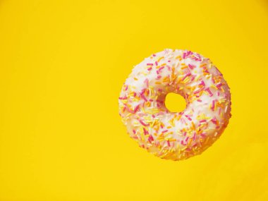 Tatlı jöleli çörek ve sarı arka planda renkli şekerleme kırıntıları serpiştirilmiş..