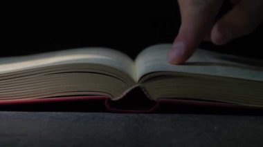 Yaşlı adamın elleri kitap okuyor. Adam parmaklarını kitabın içinde gezdiriyor..
