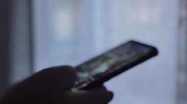 Bir erkeğin parmağı cep telefonundaki kaydırma uygulamasına dokunur. Fotoğrafları ve videoları göster.