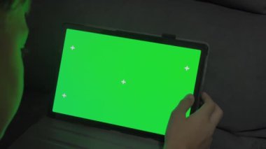 Yeşil ekranlı bir tablet bilgisayarı tutan ellerin yakın çekim görüntüsü. Video konferansı ya da çevrimiçi depolama 4k görüntüleri için bir şablon.