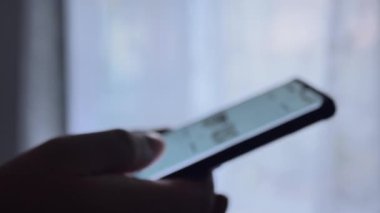 Bir erkeğin parmağı cep telefonundaki kaydırma uygulamasına dokunur. Fotoğrafları ve videoları göster.