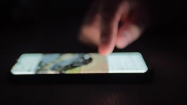 Karanlık bir odada telefonu kullanarak, odakları kesilmiş bir arabanın fotoğrafına göz atmak..