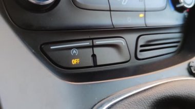 Bir adamın eli modern bir arabanın içindeki motoru çalıştırma düğmesine basar.