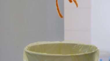 Bir adam organik atığı çöp kutusuna koyar. Ayrı atık toplama kavramı..