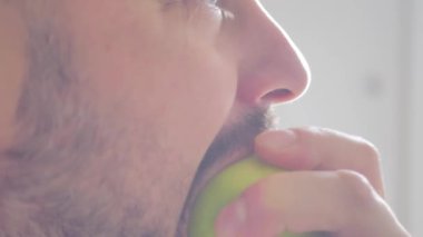 Elma yiyen adam. Taze meyve yiyen bir erkeğin ağzını kapat. Adam elma ısırıp çiğniyor. Hafif atıştırmalık Diyet ve sağlıklı yiyecekler. Ağır çekim. Doğal organik besin. Elma yiyen aç adam.