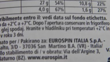 Parmak, beslenme etiketi üzerinde yavaşça hareket ediyor, bir paket yiyeceğin kalori bilgisini inceliyor, aşırı yakın çekim makro görünümü.