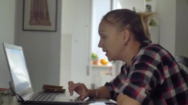 Uzaktan konuşma yapan bir kadın işçi ve bir dizüstü bilgisayar ve mikrofonlu kulaklıklar kullanarak anlaşma elde etmek..