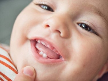 A close-up view capturing the joyful expression of a baby who is smiling and showing two little teeth. The childs eyes sparkle with delight, and theres a hint of playfulness in this candid moment clipart